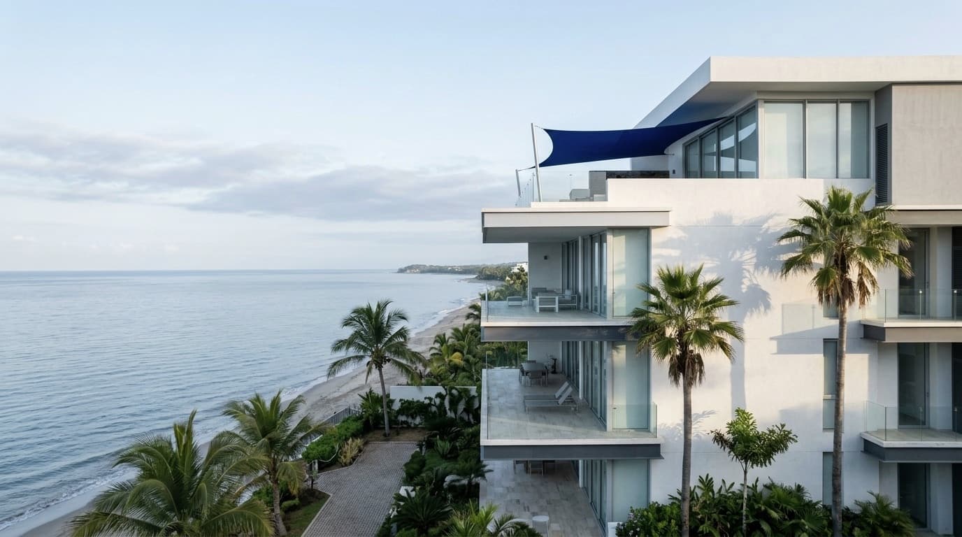 Edificio residencial contemporáneo frente al mar, entre palmeras, en la costa del Pacífico.